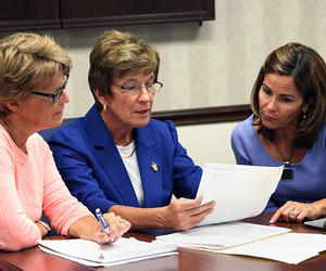 Joan M. Lappe looking over papers with two women