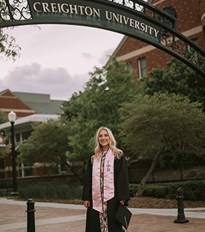 Mary Ascher in graduation robe on Creighton campus