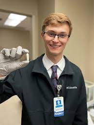 Tyler Brisso smiling in pharmaceutical lab holding suppository