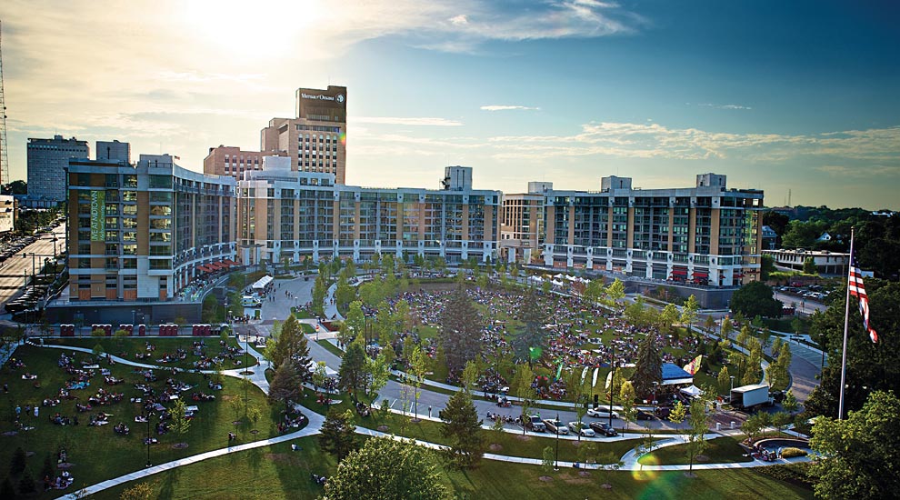 Expansive view of Creighton and Omaha's downtown with glowing sun in the sky amidst a blue sky with clouds.