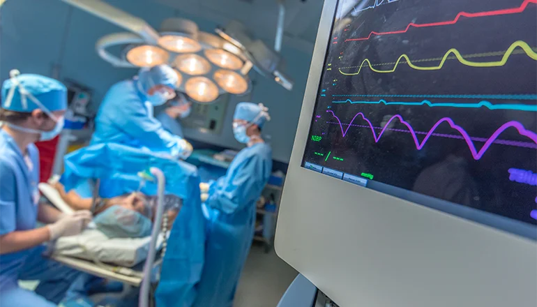 Surgeons working on patient by vitals monitor
