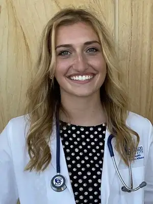 Emily Reeson in white coat with stethoscope.