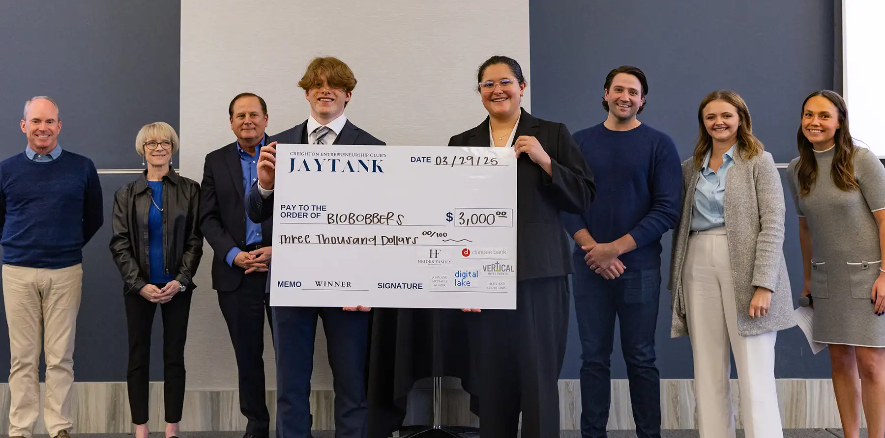 Rian Jacobs holds big check with entrepreneur partner at event.