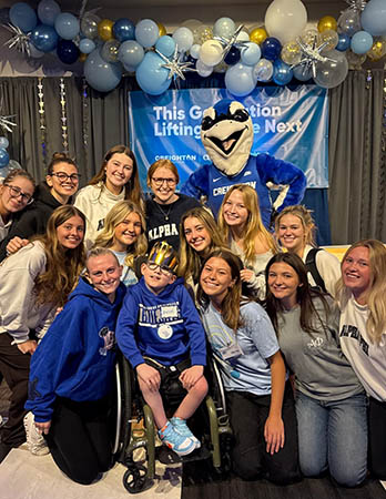 Creighton students gather with child and Billy Bluejay
