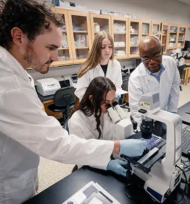 Rev. Ekpenyong in the lab with student researchers.