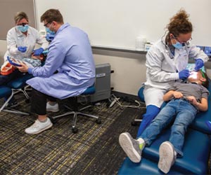 Dental professionals provide care to two children during a Healthy Smiles community outreach clinic.
