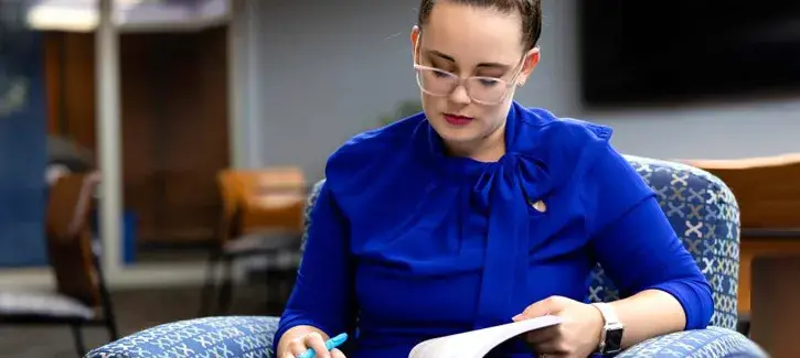 Woman studying from text book in lounge area.