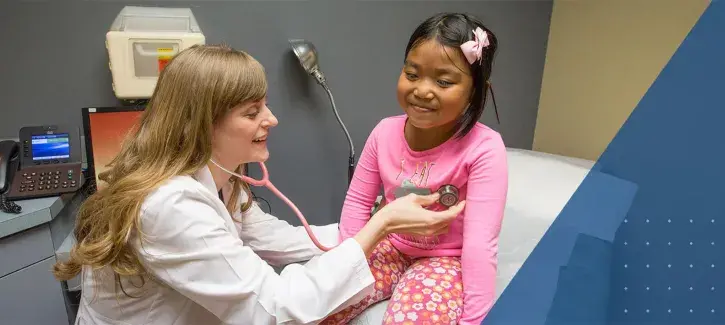 Female health professional listening to the heartbeat of a young girl.