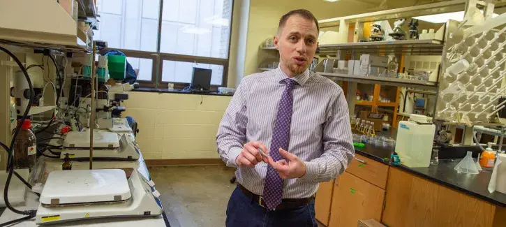 Eric Villa explaining his research in lab setting.
