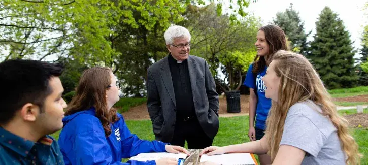 Fr. Doll with students in the Jesuit Gardens