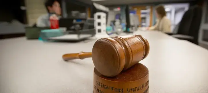 Picture of gavel on a table with people talking