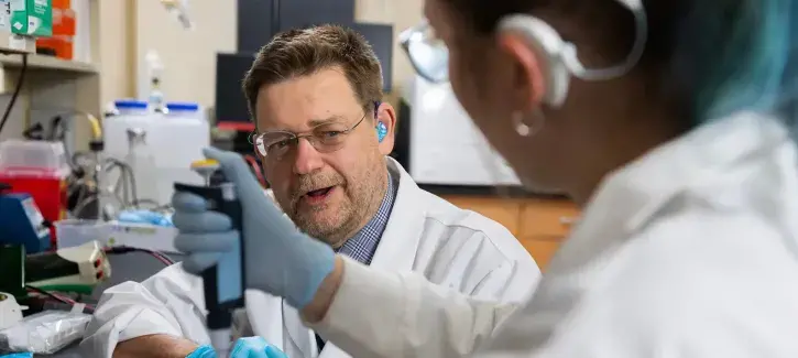 Peter Steyger collaborating with colleague in lab setting.