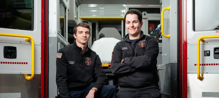 Paramedicine students posing at back of ambulance.