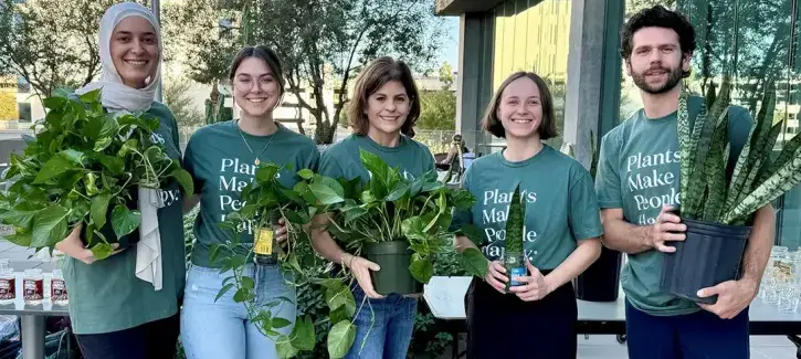 Madeline Trotter holding plants with colleagues.