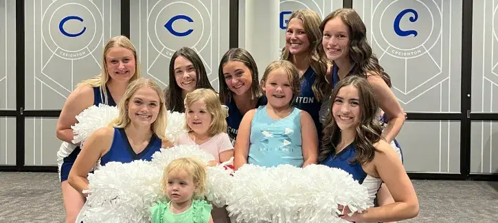 Creighton dance team posing with children.