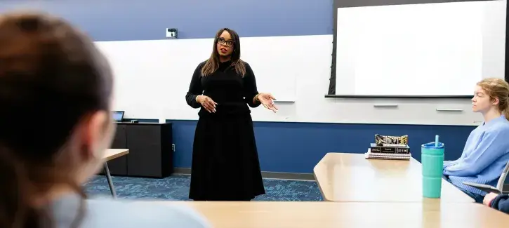 Woman in front of classroom setting.