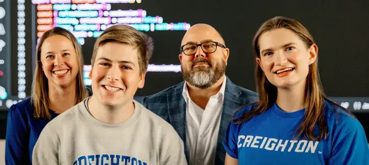 Creighton computer science members in front of data screen.