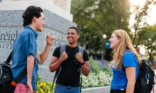 Students standing by Creighton pillar on the mall
