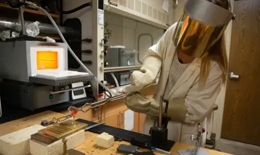 Student in Dr. Sidebottom's research lab pouring molten glass