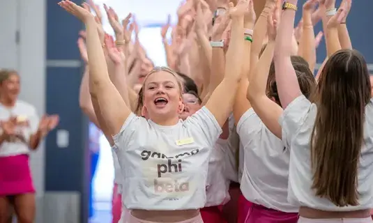 Sorority members with arms raised in unity.