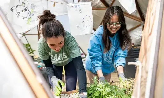 Two students working in garden setting.