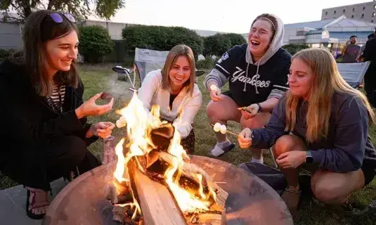 Students roasting marshmallows around a campfire