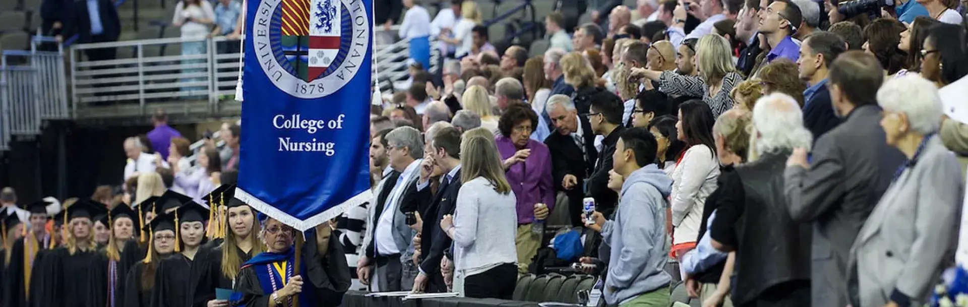 Nursing commencement ceremony with College of Nursing banner