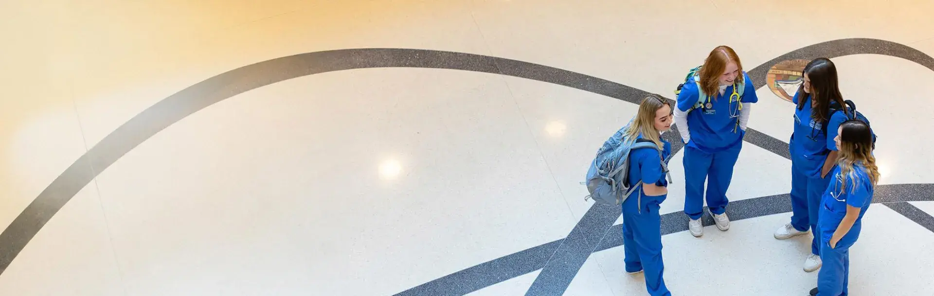 Shot from above of four nursing students in lobby of Nursing building.