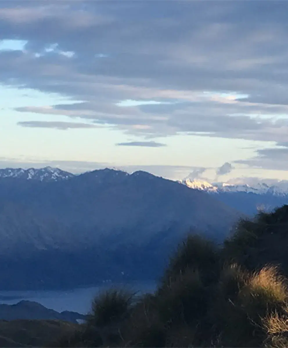A student standing on top of a mountain peak in Australia