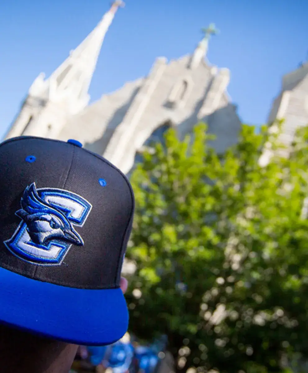 Student wearing Creighton Bluejays baseball cap on campus.