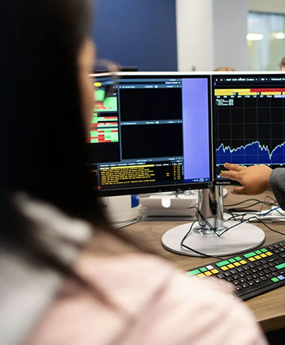 Students huddled together in front of graph data on computer monitors.