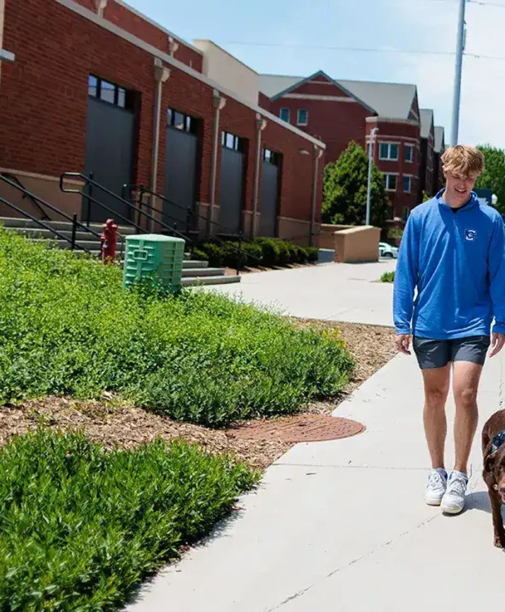 Students walking on campus with wellness dog.