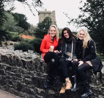 3 Creighton student sitting on stone wall