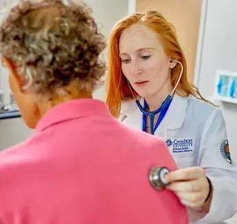 Morgan Hopp examining patient with stethoscope.