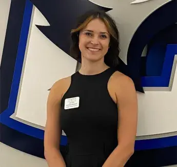 Miranda Mussack smiling by Creighton Bluejay logo.