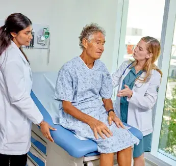 Two health professionals caring for patient in exam room.