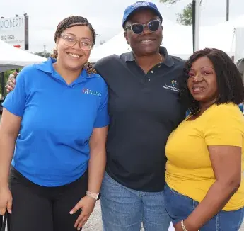 Three health equity advocates pose together at an outdoor community health event.