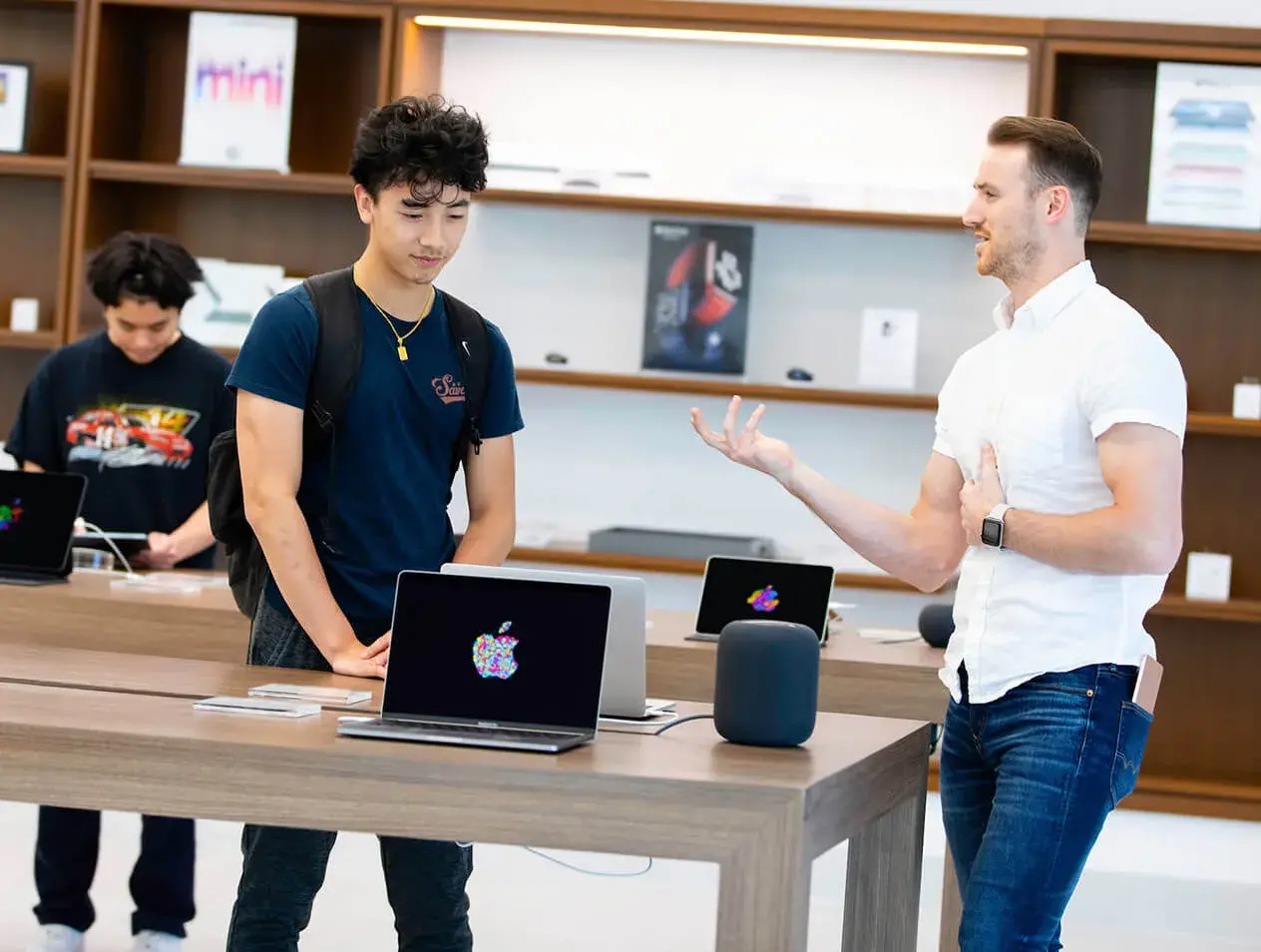 An iJay store employee explaining a laptop's features to a Creighton student