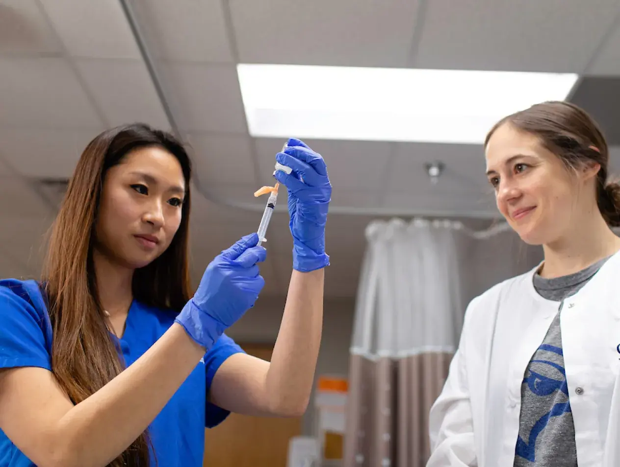 Nurse and instructor working with syringe