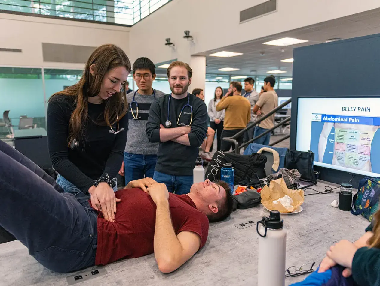 med students checking for belly pain on another student