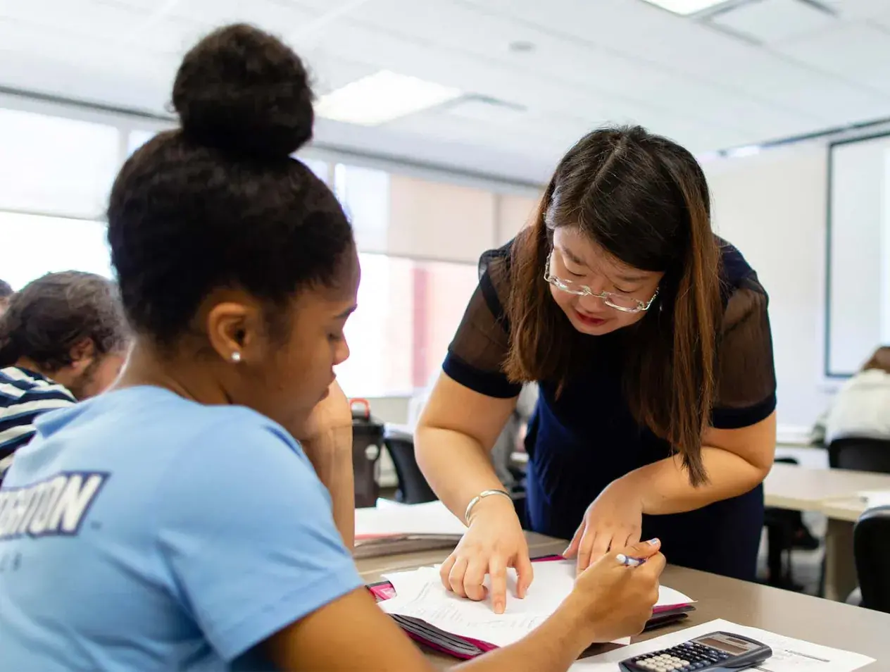 Accounting faculty working with student in classroom