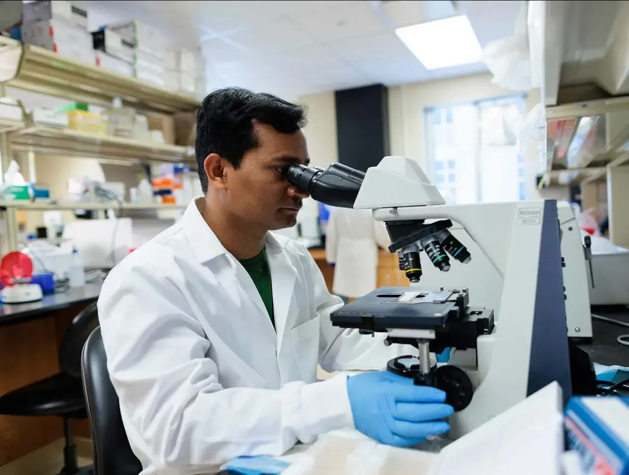 Biomedical sciences student using microscope