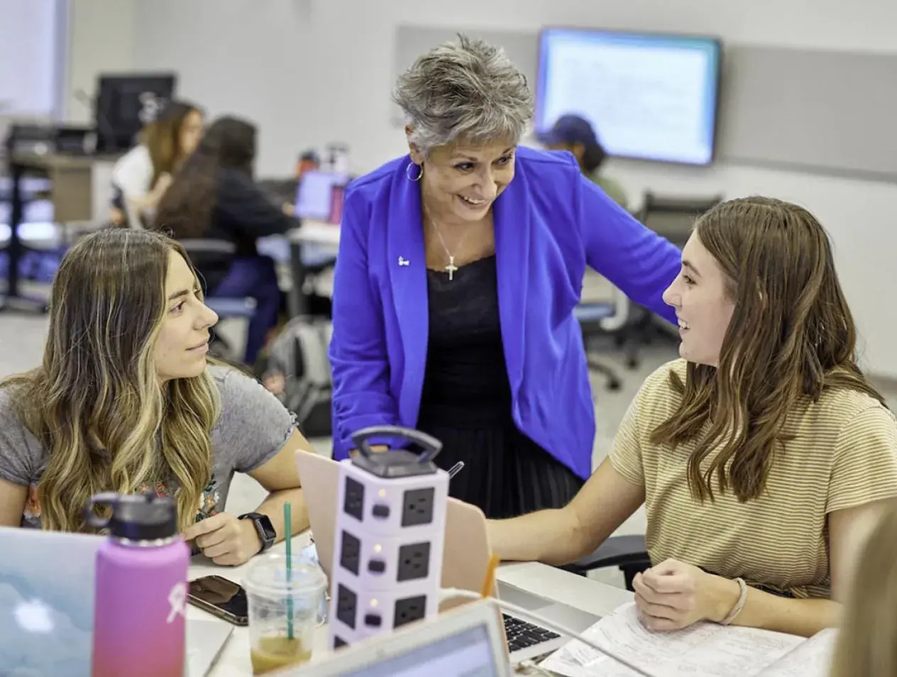 Smiling students working with professor 