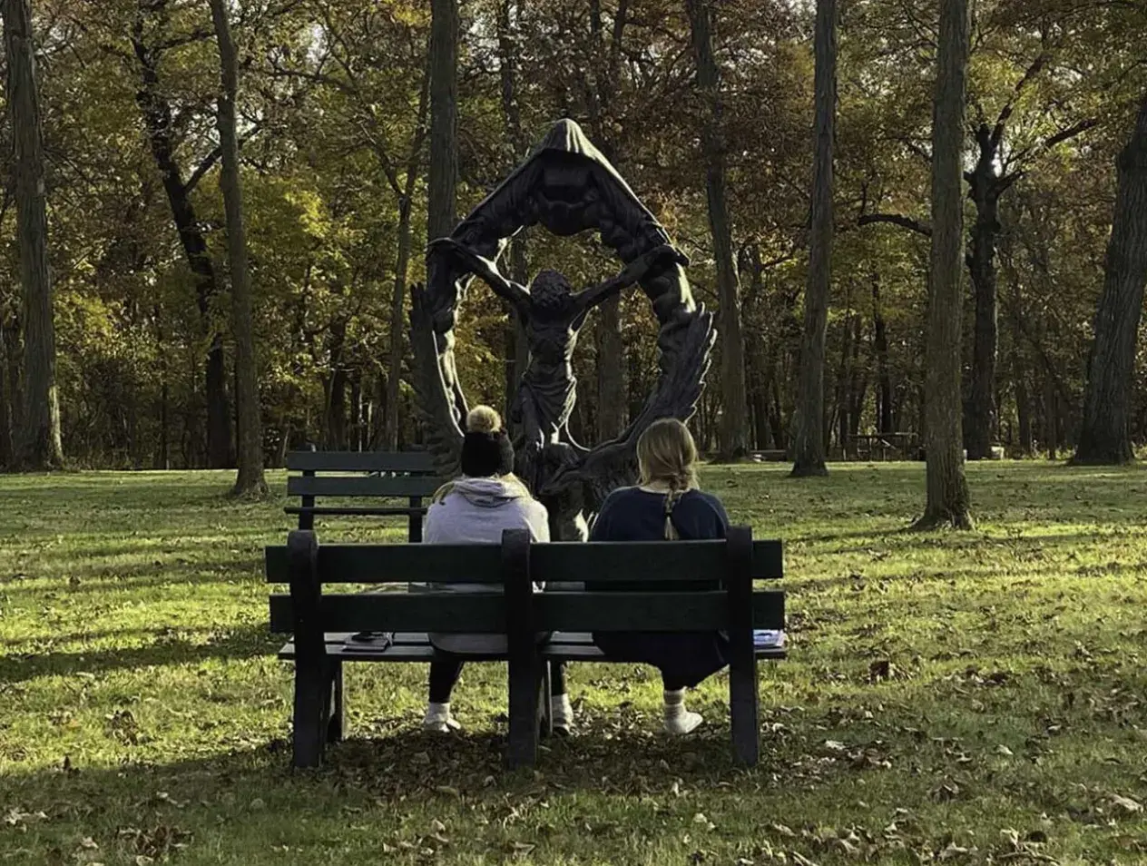 Retreat Center retreatants sitting on a bench in front of a sculpture.