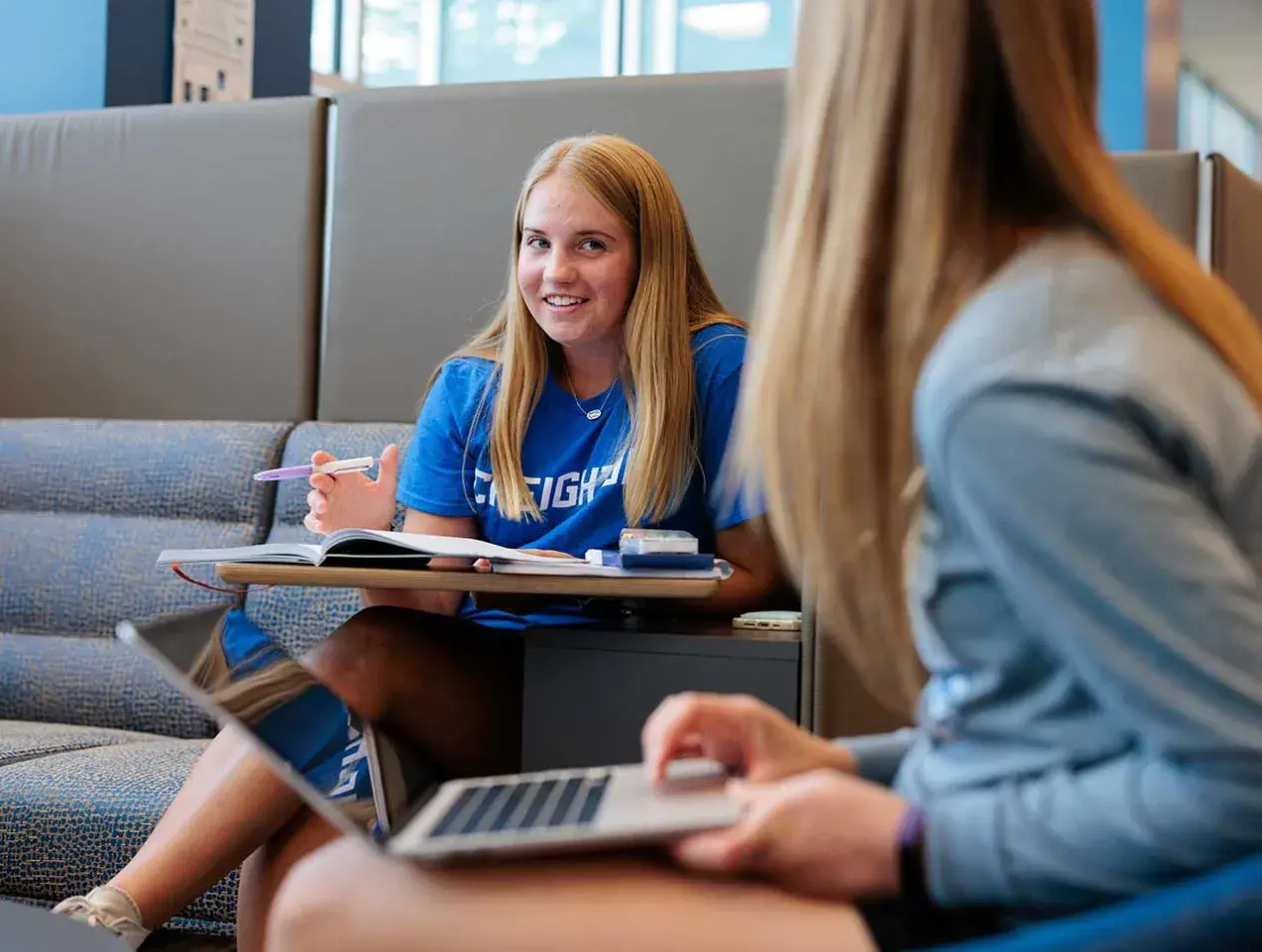 Female students conversing and studying in lounge area.