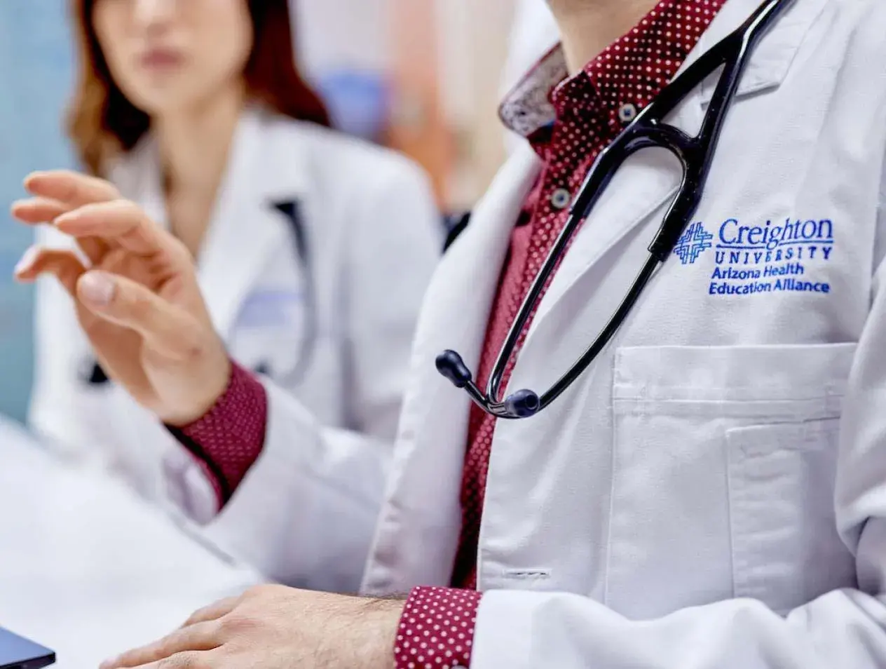 Residents in white coats in discussion.