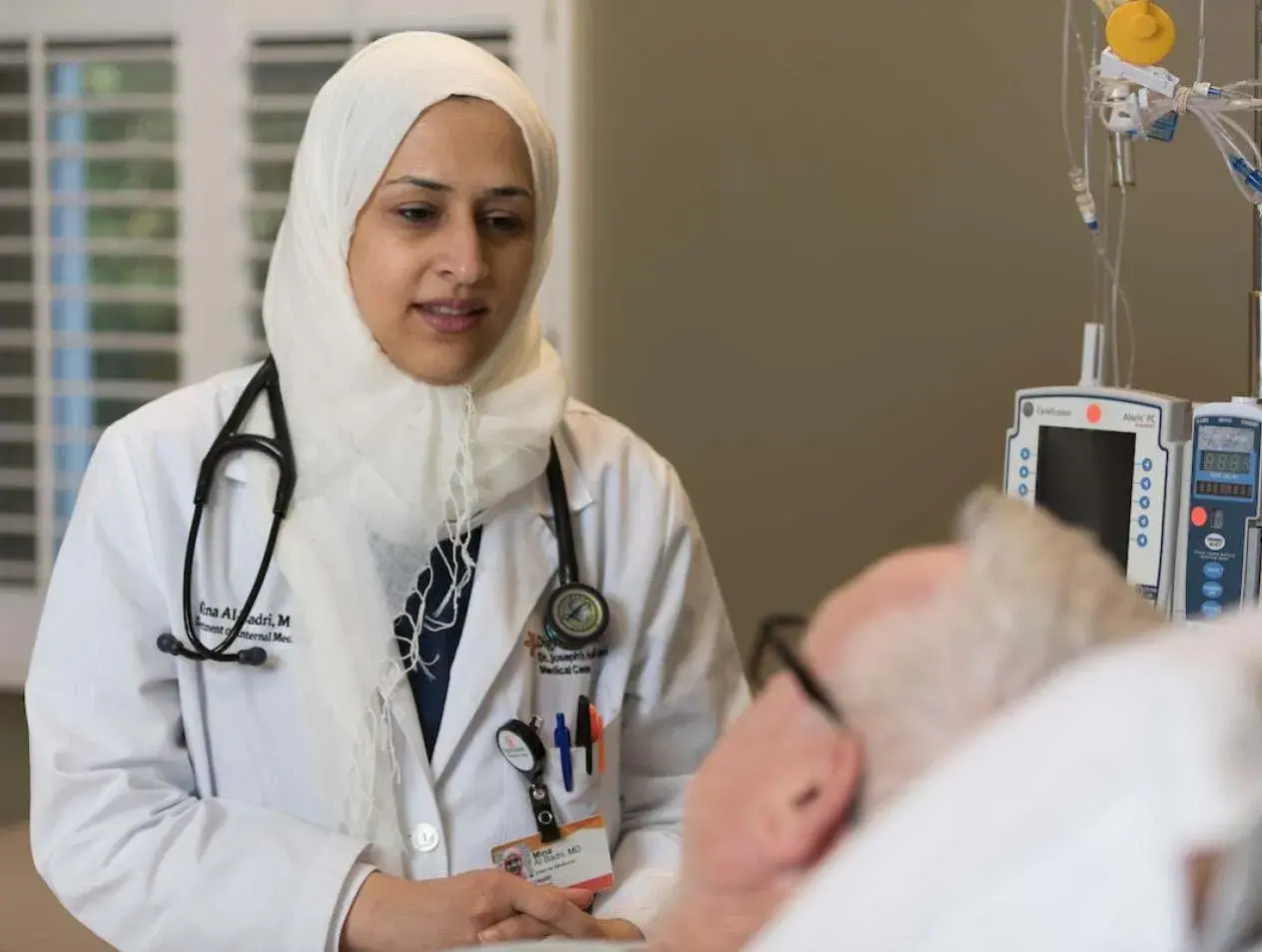 Resident with patient in hospital room.