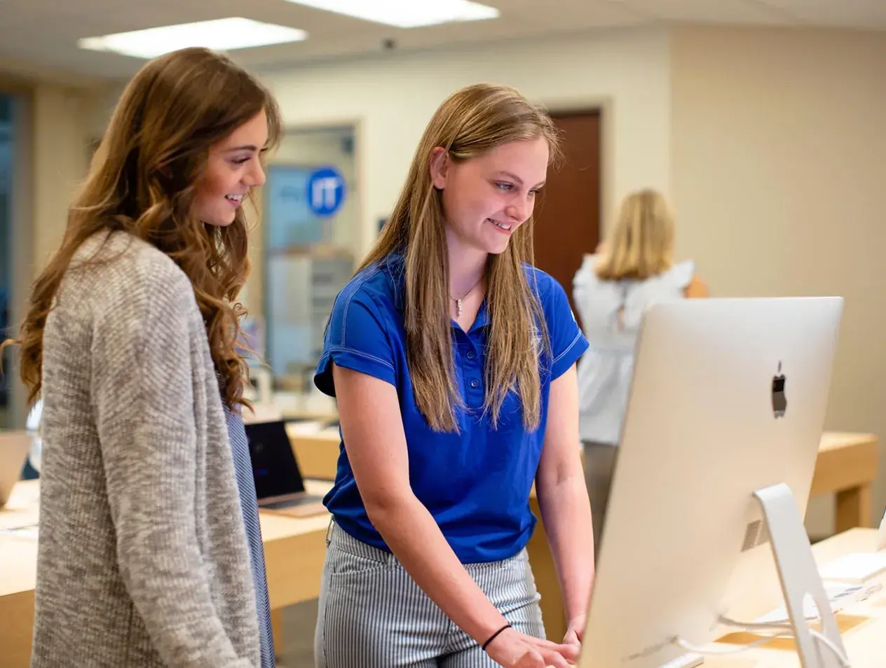 Student working with customer in campus computer shop.