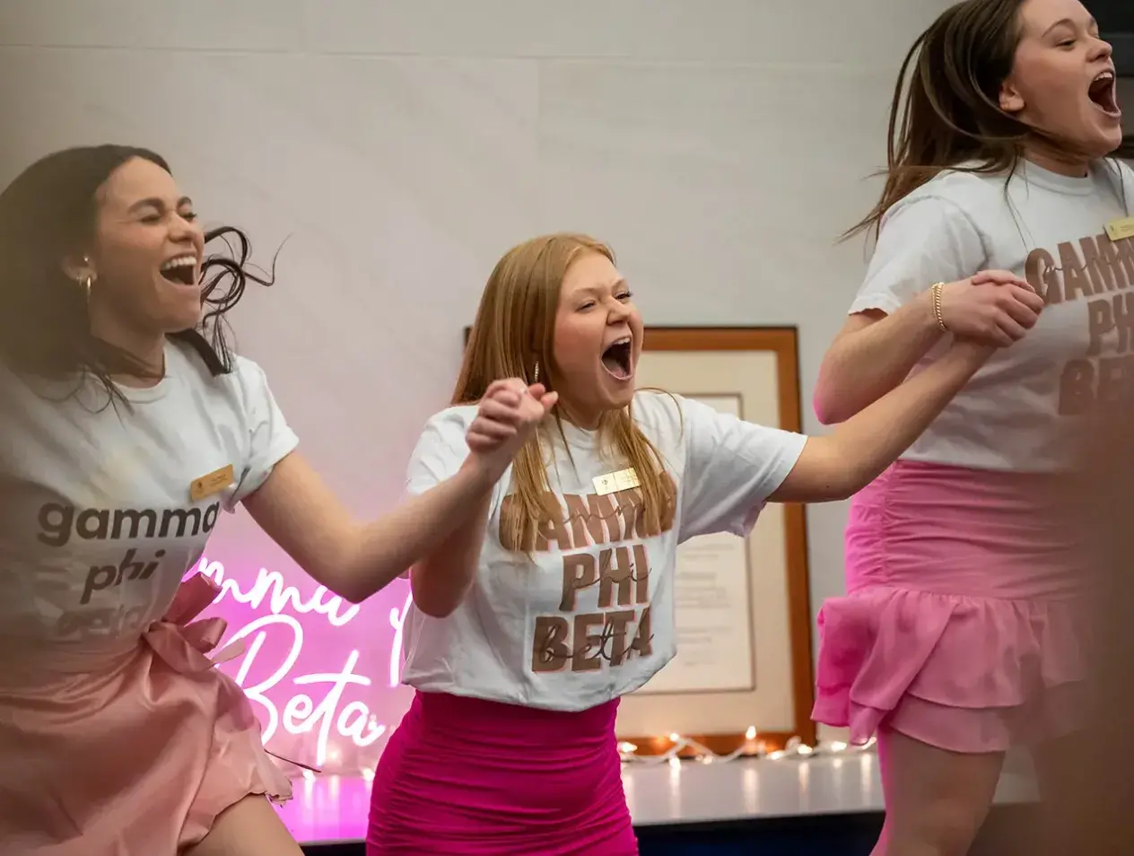 Sorority sisters holding hands and jumping in unity.