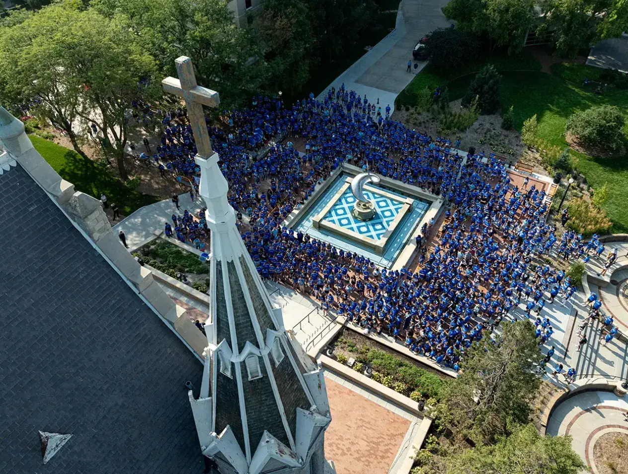 Student in mass around fountain outside St. John's church on campus.